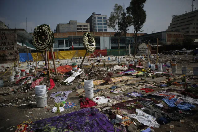 In this Monday, September 25, 2017 photo, flower wreaths, clothing, sewing supplies and a mannequin make up a memorial honoring those who died at 168 Bolivar Street when the five-story office and factory building was felled by an earthquake, in Mexico City. Businesses were located on four floors of offices at the building. Each business had no more than a half-dozen employees and there were likely no more than 50 people believed to be inside the building when the quake struck. (Photo by Rebecca Blackwell/AP Photo)