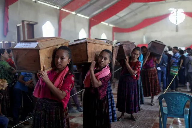 Community members carry coffins of recently exhumed human remains, the majority unidentified, dating back to Guatemala's 36-year civil war from a church to an interment site, in Sepur Zarco, Guatemala on December 10, 2021. (Photo by Sandra Sebastian/Reuters)