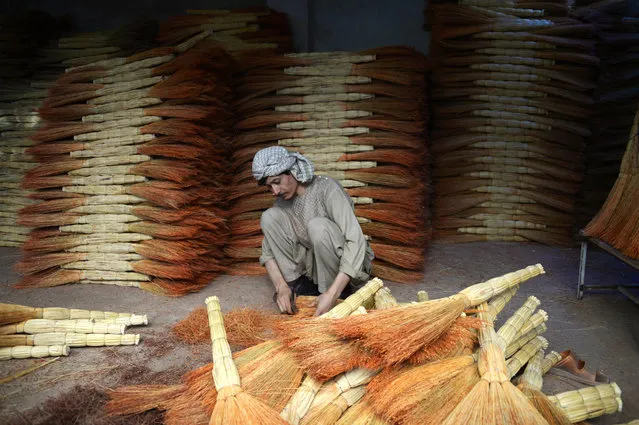 Afghan shopkeeper Naeem, 32, sorts brooms in his shop as he waits for customers on the outskirts of Mazar-i-Sharif on August 14, 2017. (Photo by Farshad Usyan/AFP Photo)