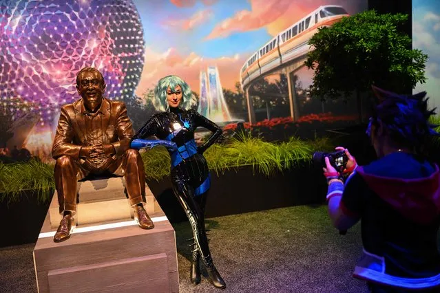 An attendee in costume poses for a picture with the Walt The Dreamer statue during the Walt Disney D23 Expo in Anaheim, California on September 9, 2022. (Photo by Patrick T. Fallon/AFP Photo)