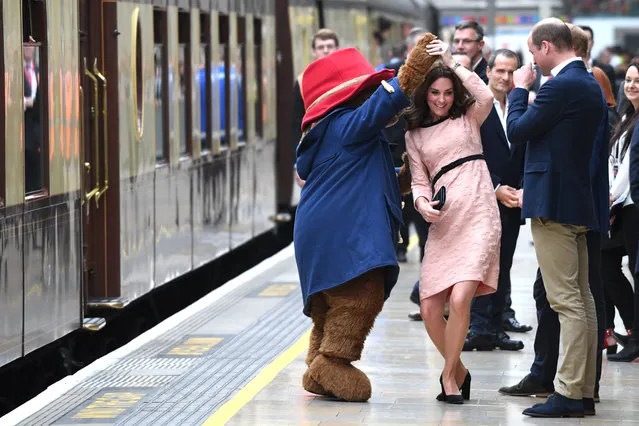 Britain's Catherine, Duchess of Cambridge, (C) dances with a person in a Paddington Bear outfit by her husband Britain's Prince William, Duke of Cambridge as they attend a charities forum event at Paddington train station in London on October 16, 2017. The Duke and Duchess of Cambridge and Prince Harry joined children from the charities they support on board Belmond British Pullman train at Paddington Station. The event was hosted by STUDIOCANAL, with support from BAFTA through its BAFTA Kids programme, and before embarking Their Royal Highnesses met the cast and crew from the forthcoming film Paddington 2. (Photo by Chris J. Ratcliffe/AFP Photo)