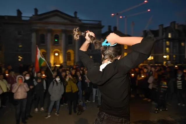 A protestor cuts her hair during a vigil in memory and solidarity for Mahsa Amini held a Trinity College Dublin, Republic of Ireland on September 28, 2022. (Photo by Bryan Meade/The Irish Times)