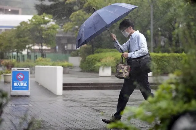 A person holds an umbrella against strong wind and rain as they walk on a bridge Tuesday, September 20, 2022, in Kawasaki, near Tokyo. A tropical storm slammed southwestern Japan with rainfall and winds Monday, leaving one person dead and another missing, as it swerved north toward Tokyo. (Photo by Eugene Hoshiko/AP Photo)