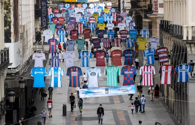 Soccer jerseys decorate a shopping street in downtown Madrid, Spain, Thursday, June 11, 2020. With virtual crowds, daily matches and lots of testing for the coronavirus, soccer is coming back to Spain. The Spanish league resumes this week more than three months after it was suspended because of the pandemic, becoming the second top league to restart in Europe after the Bundesliga was first. (Photo by Manu Fernandez/AP Photo)