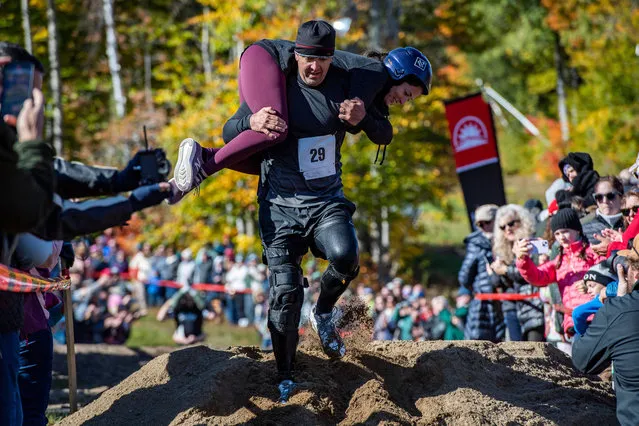 Troy and Susan Wilson make their way over a dirt pile during the 23rd North American Wife Carrying Championship at Sunday River Resort in Newry, Maine, on October 8, 2022. (Photo by Joseph Prezioso/AFP Photo)