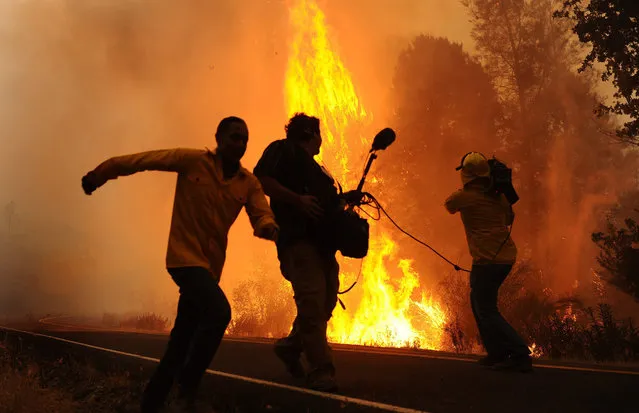 A news crew runs from flames southeast of Middletown, Calif., on Tuesday, September 15, 2015, as winds kick up the Valley fire. (Photo by Wally Skalij/Los Angeles Times/TNS)
