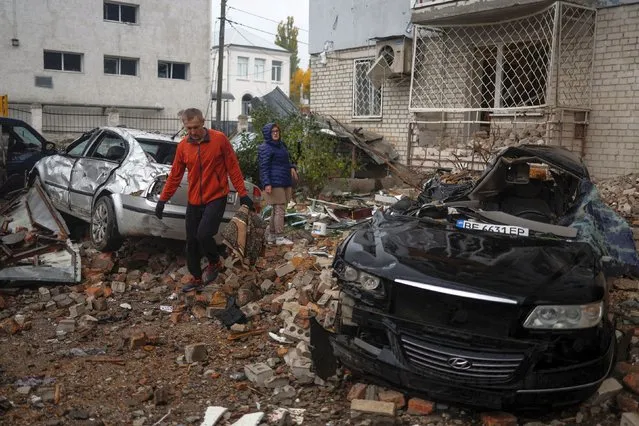 A local resident walks past cars damaged by a Russian missile attack in Mykolaiv, Ukraine on October 23, 2022. (Photo by Valentyn Ogirenko/Reuters)