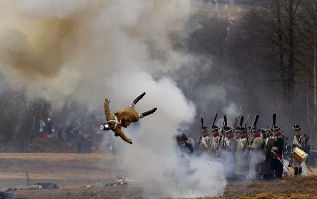 Men dressed as 1812-era Russian and French soldiers re-enact a staged battle as a dummy soldier is blown up,  near the Belarus village of Bryli, to mark the 200th anniversary of the Berezina battle during Napoleon's army retreat from Russia, November 24, 2012. The retreat across the Berezina of the remnants of Napoleon's Grand Army, which invaded Russia June 24, 1812, took place from November 26 to 29, 1812. About 50,000 people, soldiers from both sides and civilians, were killed during the crossing. (Photo by Sergei Grits/Associated Press)