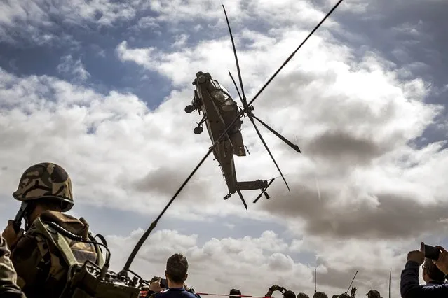 A US army AH-64 Apache attack helicopter flies over members of the Moroccan Royal Armed Forces during the second annual “African Lion” military exercise in the Tan-Tan region in southwestern Morocco on June 30, 2022. (Photo by Fadel Senna/AFP Photo)