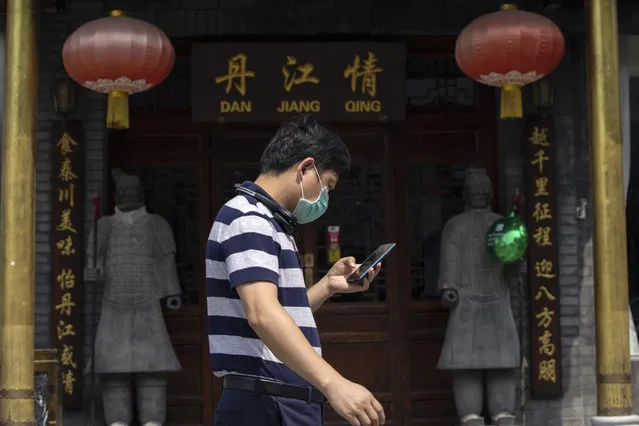 A man wearing a mask to curb the spread of the coronavirus walks past replicas of the Terracotta Warriors outside a restaurant in Beijing on Wednesday, July 8, 2020. (Photo by Ng Han Guan/AP Photo)