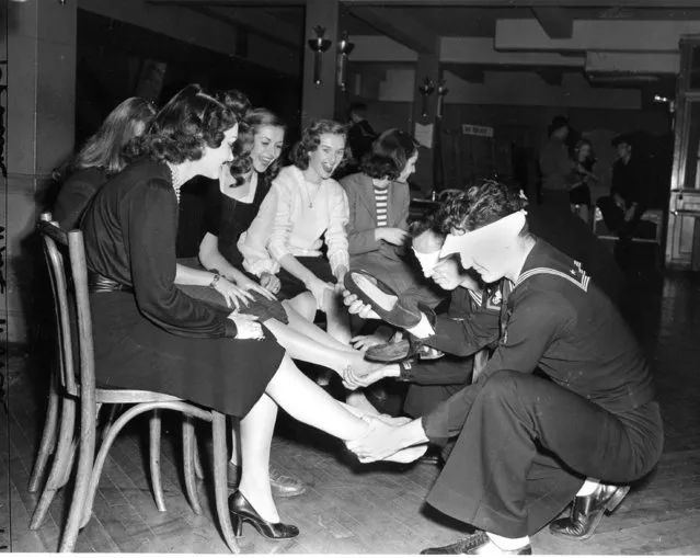 Blind folded servicemen select a woman's shoe from a pile and try to fit it on the correct  foot as they play the slipper game with United Service Organizations (USO) hostesses at the 2-4-1 Canteen in New York City, December 12, 1944. (Photo by AP Photo)