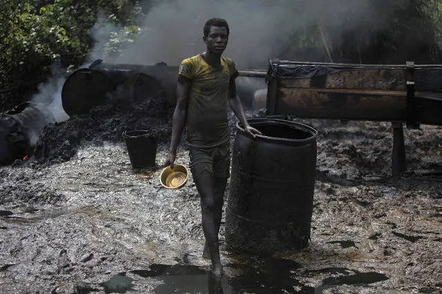 A crude oil refinery worker stands in front of a locally made burner in an illegal oil refinery site near river Nun in Nigeria's oil state of Bayelsa, November 27, 2012. The worker said that he had been doing the job for two years and earned the equivalent of around $60 a day. (Photo by Akintunde Akinleye/Reuters)