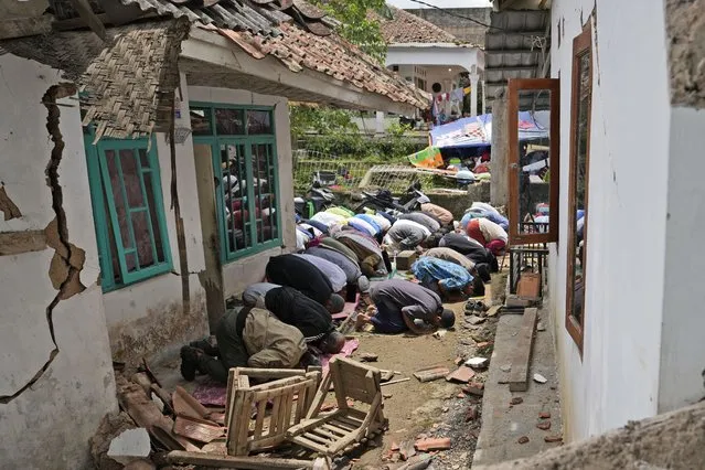 Muslim men perform a Friday prayer outside a mosque badly damaged in Monday's earthquake, in Gasol village, Cianjur, West Java, Indonesia, Friday, November 25, 2022. The quake on Monday killed hundreds of people, many of them children and injured thousands. (Photo by Achmad Ibrahim/AP Photo)