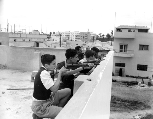 Members of the National Military Organization Irgun Zvai Leumi are armed with rifles, revolvers and automatic weapons as they take position on the rooftop of a Jewish house in case of Arab attack on the Jaffa-Tel Aviv border in the Manshiah Jewish quarter in Tel Aviv on December 27, 1947. The Zionist guerrilla force began an armed revolt against British rule in Palestine. (Photo by James Pringle/AP Photo)
