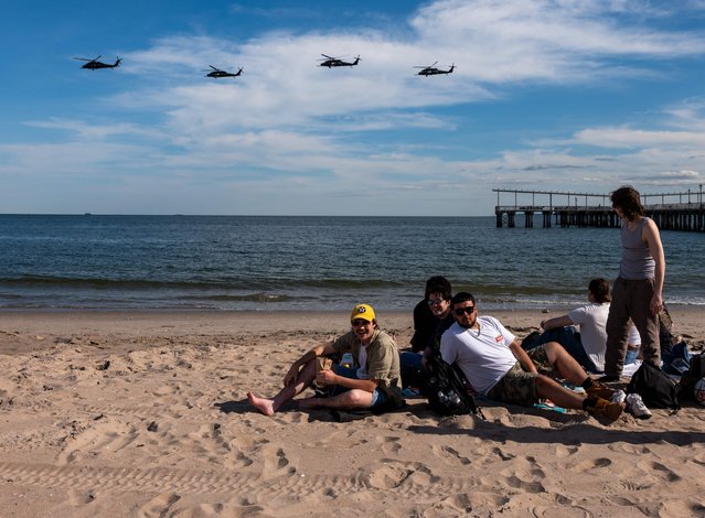 People enjoy a day at Coney Island as a line of helicopters fly by days before the Memorial Day weekend on May 20, 2025 in New York City. The federal holiday is the unofficial start of the summer season, and the large crowds that follow as the weather warms. (Photo by Spencer Platt/Getty Images/AFP Photo)