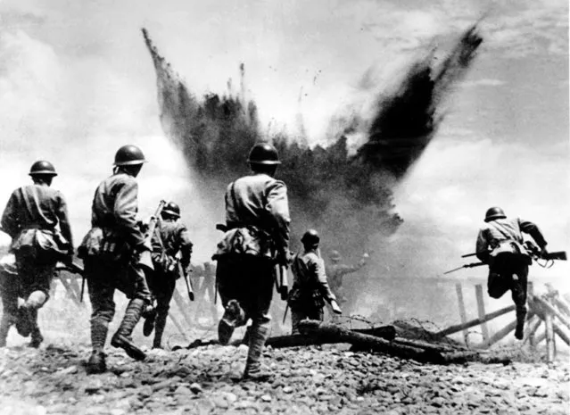 Japanese infantrymen advance with rifles and grenades, leaping over barbed wire and preceded by an artillery barrage, in the Peking sector in China on August 19, 1937 during the Second Sino Japanese War.  Heavy casualties occurred on both sides, but Chinese losses outnumbered the Japanese five to one. (Photo by AP Photo)