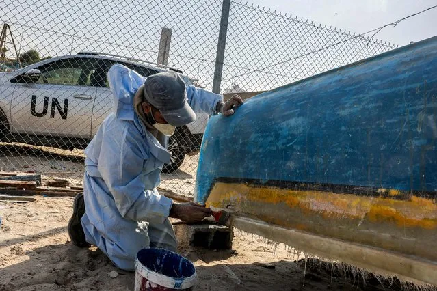 A craftsman uses fibreglass to repair a fishing boat at a workshop supervised by the United Nations at the Gaza seaport on November 29, 2022, after Israel allowed the material to the Palestinian enclave for the first time since 2007 under international supervision. (Photo by Mohammed Abed/AFP Photo)