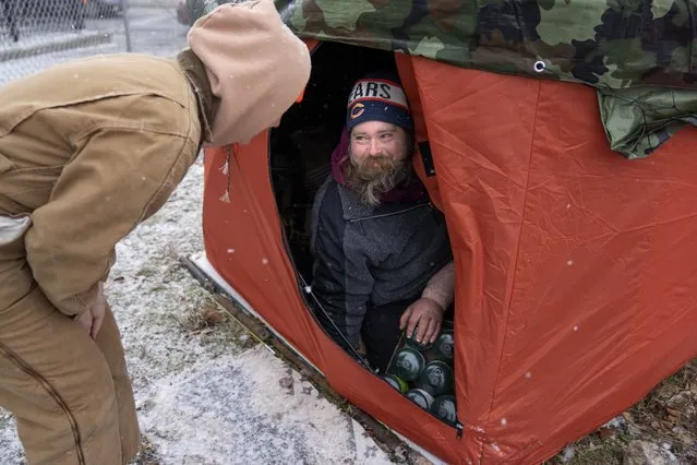 “Orange tent project” volunteer Morgan Mcluckie, left, speaks with unhoused person Peter Zielinski after giving him bottles of propane to use with his portable heater as cold and snowy weather moves in Thursday, December 22, 2022, in Chicago. Officially the nonprofit “Feeding People Through Plants”, founder Andy Robledo set out to find unhoused people and give them large orange tents used for ice fishing to replace other tents and shelters that are inadequate for severe winter weather. (Photo by Erin Hooley/AP Photo)