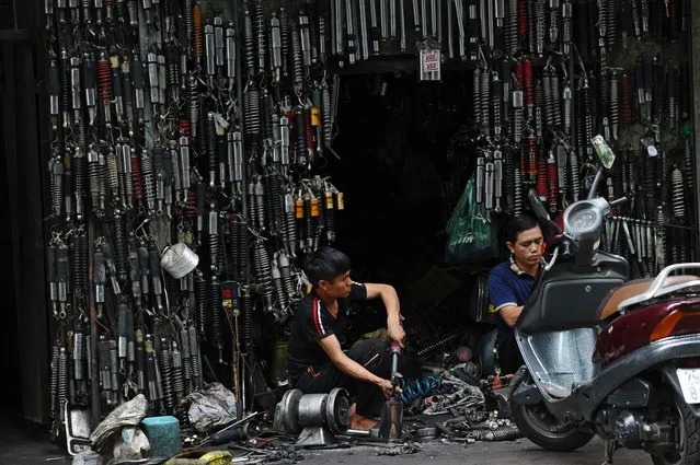Mechanics work at roadside shop specialized in repairing motorbike suspension systems in downtown Hanoi on September 17, 2015. (Photo by Hoang Dinh Nam/AFP Photo)