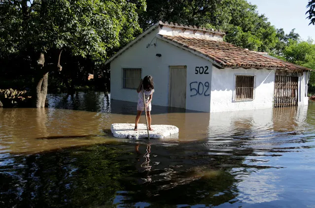 A young girl uses a piece of styrofoam as a paddle board next to a flooded home after heavy rains caused the river Paraguay to overflow, on the outskirts of Asuncion, Paraguay January 23, 2018. (Photo by Jorge Adorno/Reuters)