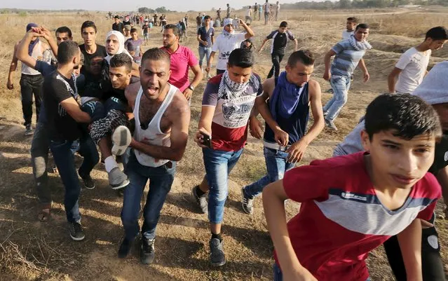 A wounded Palestinian protester is evacuated after he was shot by Israeli troops near the border between Israel and Central Gaza Strip October 13, 2015. (Photo by Ibraheem Abu Mustafa/Reuters)