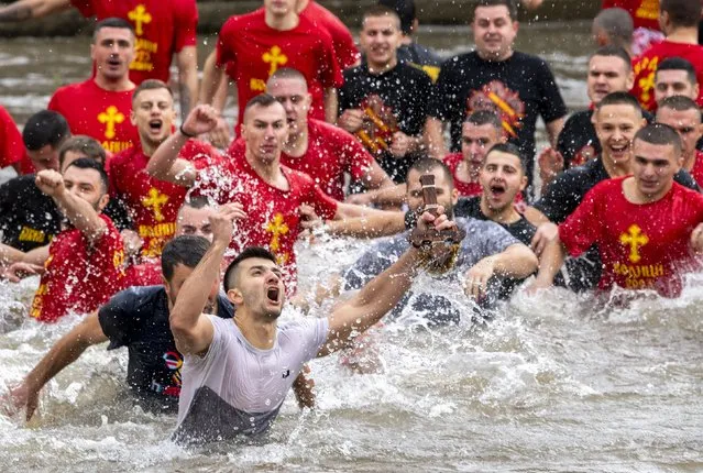 Kristijan Nineski, 26-years-old Macedonian, catches the cross which was thrown in the Vardar river by the head of the Macedonian Orthodox church, Archbishop Stefan, during Epiphany day celebrations in Skopje, Republic of North Macedonia, 19 January 2023. Young Macedonians jump into the icy water as they compete to catch the cross in the Vardar river in Skopje on Epiphany day. According to the beliefs of the Eastern Orthodox church the first man who catches the cross thrown into the water will be healthy throughout the whole year. (Photo by Georgi Licovski/EPA/EFE)