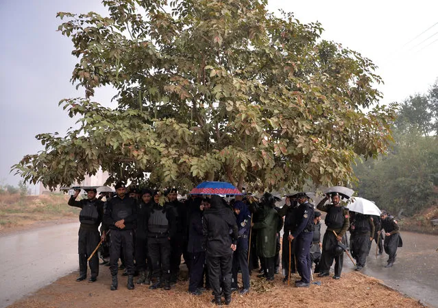 Pakistani policemen gather under a tree during heavy rain near an accountability court where ousted Pakistani prime minister Nawaz Sharif appear before the corut to face corruption charges in Islamabad on November 15, 2017. In late July the Supreme Court made Sharif the 15th premier in Pakistan's 70-year history to be ousted before completing a full term, after a corruption investigation against him. (Photo by Aamir Qureshi/AFP Photo)
