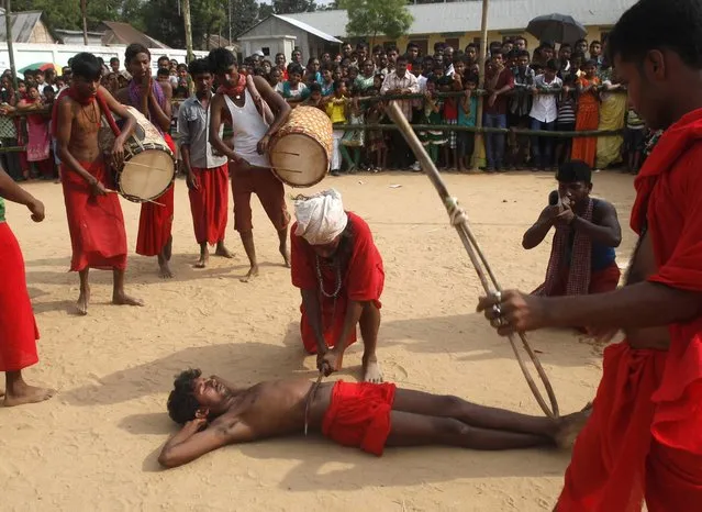 A Hindu priest presses his sword against his disciple as they perform a stunt during the annual Shiva Gajan religious festival at Pratapgarh, on the outskirts of the northeastern Indian city of Agartala, April 14, 2013. Hundreds of faithful devotees offer sacrifices and perform acts of devotion during the festival in the hopes of winning the favour of Hindu god Shiva and ensuring the fulfillment of their wishes and also to mark the end of the Bengali calendar year. (Photo by Jayanta Dey/Reuters)