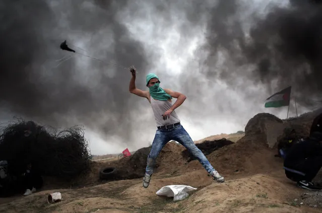 A Palestinian protester hurls stones using a sling shot during clashes with Israeli soldiers on the Israeli border with Gaza in Bureij, central Gaza Strip, Friday, November 6, 2015. (Photo by Khalil Hamra/AP Photo)