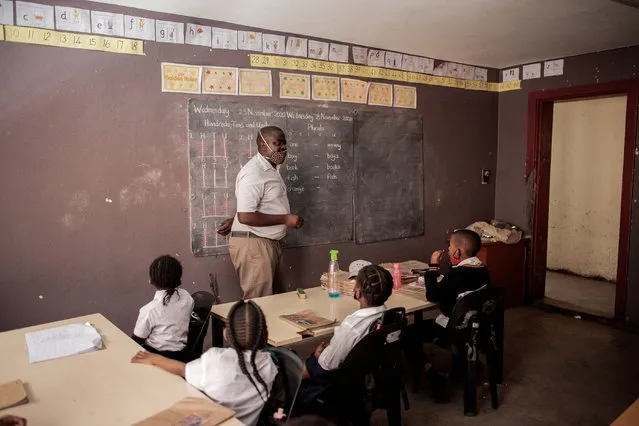 A teacher gives lesson in a classroom of Albert Street Primary School, in Johannesburg CBD, on November 25, 2020. The school was created 12 years ago to provide basic education to the children of asylum seekers and refugees. Due the economic consequences of the COVID-19 coronavirus pandemic, the number of students hosted in the school decreased from 168 to 50, creating a drastic reduction of staff. The lack of basic services as electricity is also a challenge. (Photo by Luca Sola/AFP Photo)