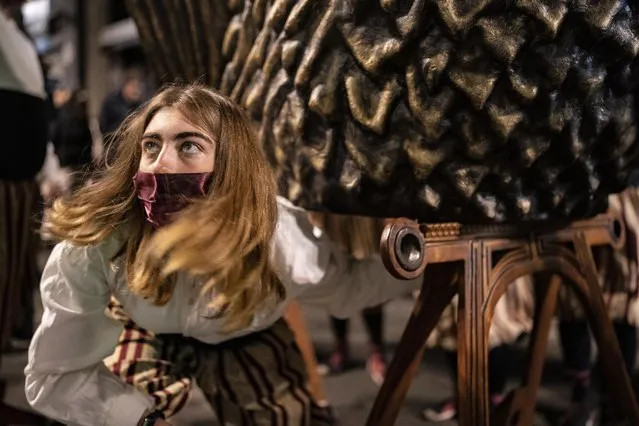 A performer removes a traditional eagle costume after performing “El Ball de l'Àliga” (Dance of the Eagle) during Saint Eulàlia fesitivities in Barcelona, Spain, Friday, February 11, 2022. After two years of canceled or muted celebrations due to the pandemic, this Mediterranean city went all-out to celebrate the feast, or “fest” in the Catalan language, of its patron. (Photo by Joan Mateu Parra/AP Photo)