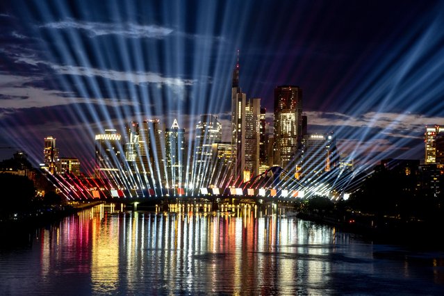 A test run of a light show illuminates the sky and the river Main in Frankfurt, Germany, late Tuesday, June 11, 2024. The show is part of the city's entertainment program on occasion of the Euro 2024 soccer tournament and will take place every evening during the tournament. (Photo by Michael Probst/AP Photo)