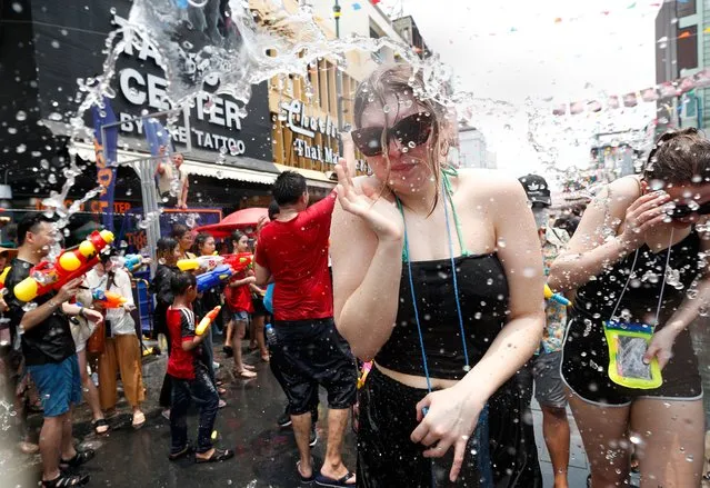 A tourist reacts during a water gun battle as part of the annual Songkran festival, also known as water festival, the traditional Thai New Year celebrations, at the tourist spot of Khao San Road in Bangkok, Thailand, 13 April 2023. Thailand celebrates its first water-splashing Songkran festival following a three-year pause due to the COVID-19 pandemic. Songkran is celebrated with splashing water and putting powder on each other's faces as a symbolic sign of cleansing and washing away the sins from the old year. (Photo by Rungroj Yongrit/EPA/EFE/Rex Features/Shutterstock)