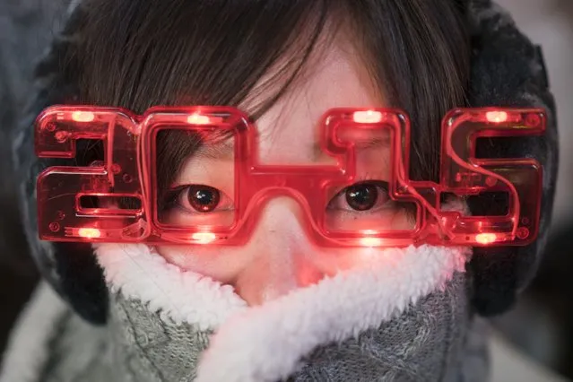 A woman sports 2015 glasses while taking cover from the cold weather during New Year's Eve celebrations in Times Square, New York December 31, 2014. (Photo by Zoran Milich/Reuters)