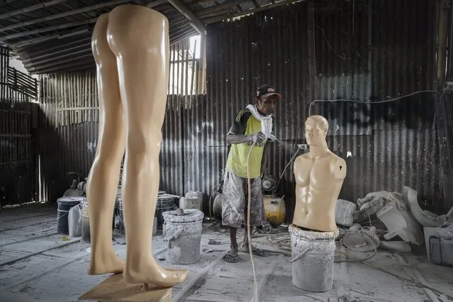 An Indonesian labourer sprays paint on to a mannequin at a small scale mannequins factory in Jakarta, Indonesia, 23 September 2016. The factory produces fiberglass mannequins to be distributed to shopping centers. Full body mannequins of different types are sold for IDR 200.000 (14 Euro) each. (Photo by Mast Irham/EPA)