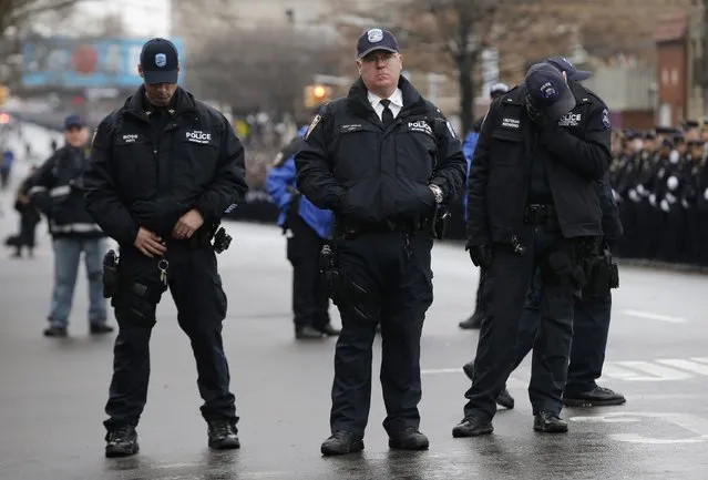 Police stand in silence on the street as they listen to the funeral service for New York Police Department officer Wenjian Liu in the Brooklyn borough of New York January 4, 2015. (Photo by Mike Segar/Reuters)
