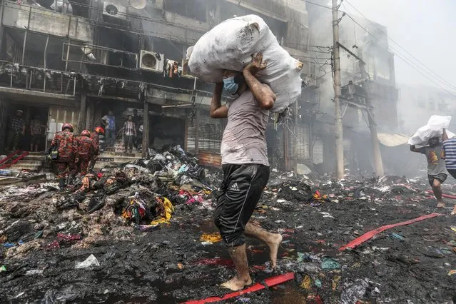 Shopkeepers salvage their goods from nearby shops as a fire rages at a popular market for cheaper clothes in Bangladesh's capital Dhaka, Bangladesh, Tuesday, April, 4, 2023. The fire broke out at Bangabazar Market in Dhaka on Tuesday. (Photo by Mahmud Hossain Opu/AP Photo)