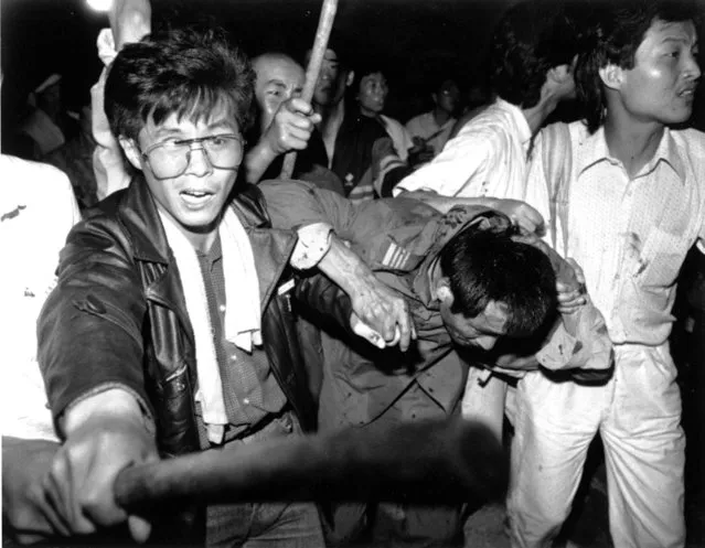 A captured tank driver is helped to safety by students as the crowd beats him during the bloody June 4 1989 army crackdown on the pro-democracy movement at Beijing's Tiananmen Square. (Photo by Reuters)