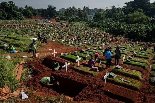 Grave diggers work on a grave at Pondok Rangon public cemetery, reserved for suspected COVID-19 victims on December 24, 2020 in Jakarta, Indonesia. Indonesia is still struggling to contain thousands of new daily cases of coronavirus amid an easing of rules to allow economic activity to resume, as its economy is ravaged by the virus and a new year approaches. A country of 270 million spread over a vast archipelago of islands, Indonesia has the worst outbreak in Southeast Asia, and also has the lowest testing rates in the region. The government announced this week that it will distribute enough vaccines to cover 181 million people starting in January – a glimmer of hope after what has been a grim year. (Photo by Ulet Ifansasti/Getty Images)