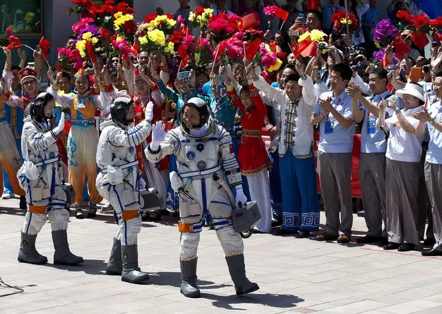 China's astronauts Wang Yaping, Zhang Xiaoguang and Nie Haisheng wave as they leave the Jiuquan satellite launch center for their launch site near Jiuquan in western China's Gansu province, on June 11, 2013. (Photo by Andy Wong/Associated Press)