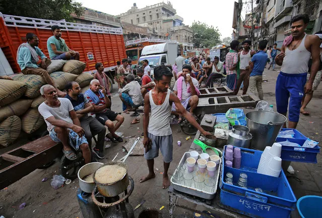 Labourers take their morning tea from a roadside vendor in the old quarters of Delhi, India on June 6, 2018. (Photo by Amit Dave/Reuters)