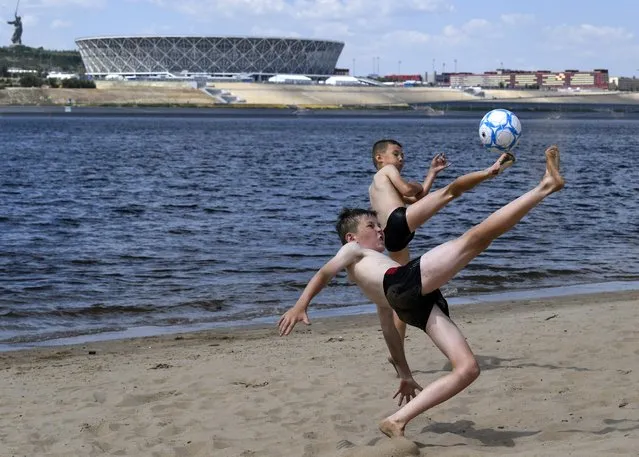 Children play football on a bank of the Volga river in front of the Volgograd arena, a venue of the Russia 2018 World Cup football tournament, on 20 June 20 , 2018, in Volgograd. (Photo by Philippe Desmazes/AFP Photo)