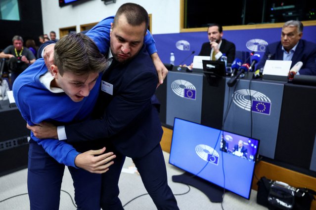 A security member grabs a protester as Hungarian Prime Minister Viktor Orban speaks during a press conference with MEP Kinga Gal, Vice-President of Patriots for Europe Group, at the European Parliament in Strasbourg, France on October 8, 2024. (Photo by Yves Herman/Reuters)
