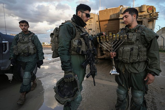 Israeli soldiers light a candle on the seventh night of Hanukkah before being deployed to the Gaza Strip near the Israeli-Gaza border in southern Israel, Tuesday, December 31, 2024. (Photo by Tsafrir Abayov/AP Photo)