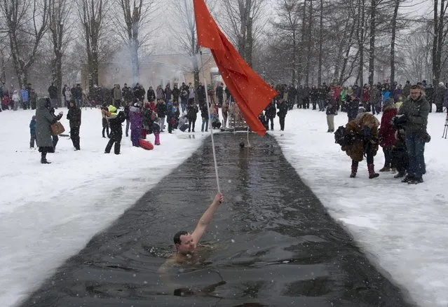 A Russian man swims in the icy water with a Soviet flag in St. Petersburg, Russia, Sunday January 25, 2015, marking the 71st anniversary of the breaking the Nazi siege of Leningrad during WWII. The temperature in St. Petersburg is around -3 C (27 F). Ice swimming is an annual part of celebrations marking the anniversary of the battle that broke the Siege of Leningrad, the city which is now known as St. Petersburg. (Photo by Dmitry Lovetsky/AP Photo)