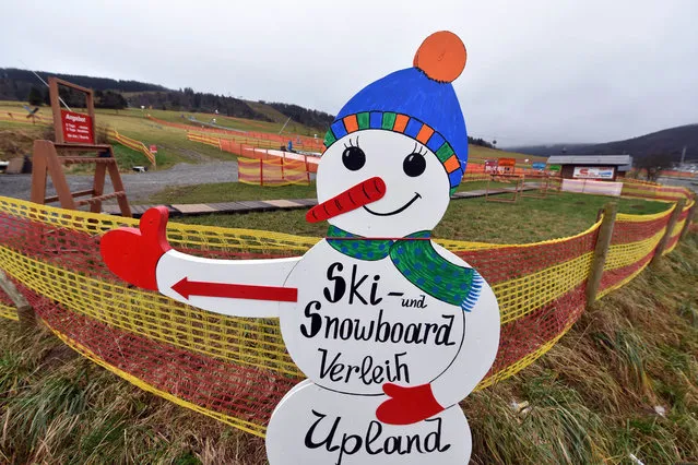 In this photo taken Tuesday, December 22, 2015, a snowman figure shows the way to a ski and snowboard rental next to snowless slopes in Willingen, central Germany. The December weather in Germnay is unusal warm with temperatures above 10 degrees Celsius (50 Fahrenheit). (Photo by Uwe Zucchi/DPA via AP Photo)