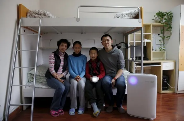 Jiang Zhen, his wife Zhang Fang and their children Doudou (2nd R) and Dudu (2nd L) pose with a portable device that measures air quality and an air purifier in the children's room, on the second day after China's capital Beijing issued its second ever “red alert” for air pollution, in Beijing, China, December 20, 2015. (Photo by Kim Kyung-Hoon/Reuters)