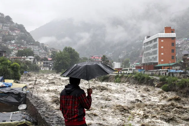A man looks at a swollen River Beas following heavy rains in Kullu, Himachal Pradesh, India, Sunday, July 9, 2023. According to local reports heavy rain fall has triggered landslides, damaged houses and caused loss of lives. (Photo by Aqil Khan/AP Photo)