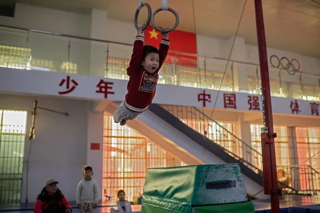 In this picture taken on January 12, 2021, a young gymnast trains at the Li Xiaoshuang Gymnastics School in Xiantao, Hubei province. (Photo by Nicolas Asfouri/AFP Photo)