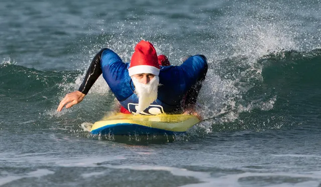 A surfer dressed as Santa tries to get to his feet as he braves the cold seas and near flat waves during the annual Surfing Santa as part of the Santa Run and Surf 2016 at Fistral Beach in Newquay on December 4, 2016 in Cornwall, England. (Photo by Matt Cardy/Getty Images)
